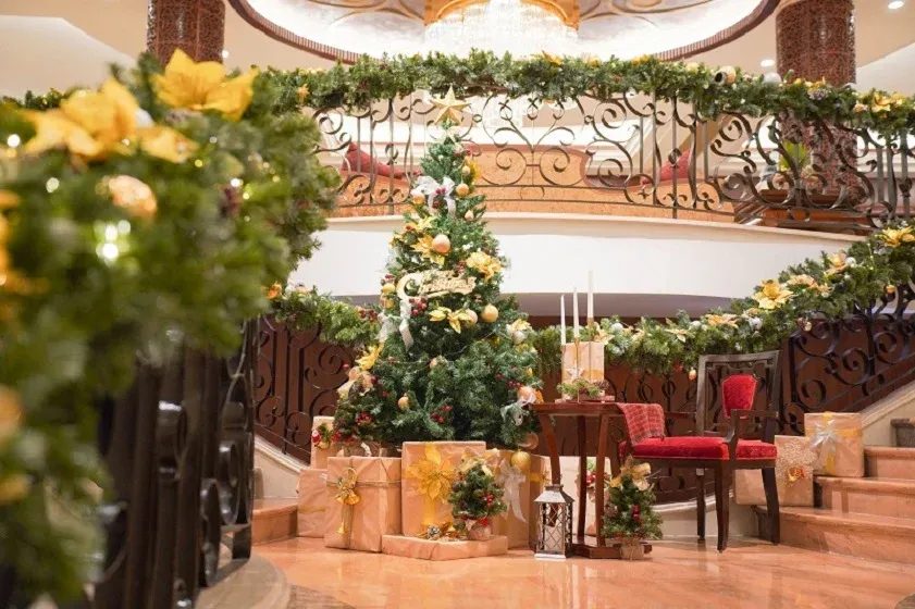 Người lớn và trẻ em đang cùng nhau trang trí cây thông Noel với đèn và phụ kiện