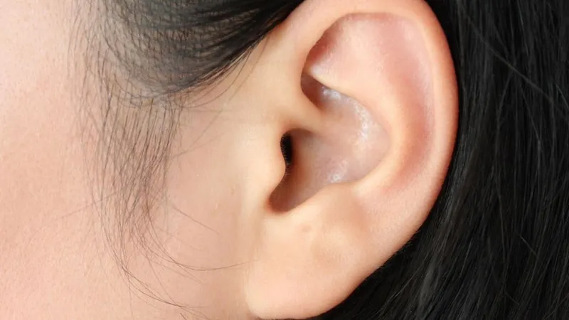 Một người phụ nữ đang cầm tay lên tai, thể hiện sự khó chịu do tai nóng